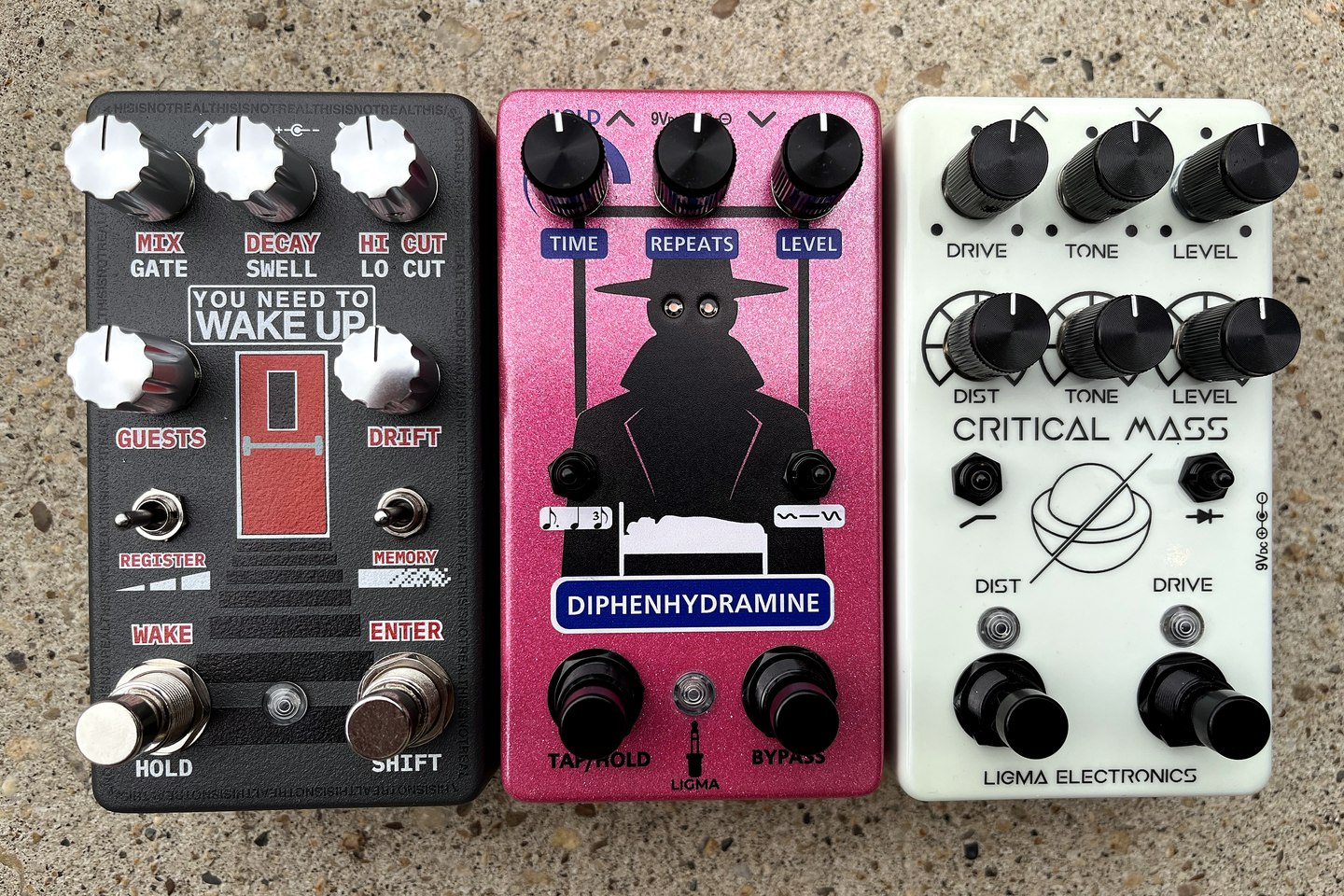 You Need to Wake Up, Hat Man Delay, and Critical Mass pedals standing side by side on concrete